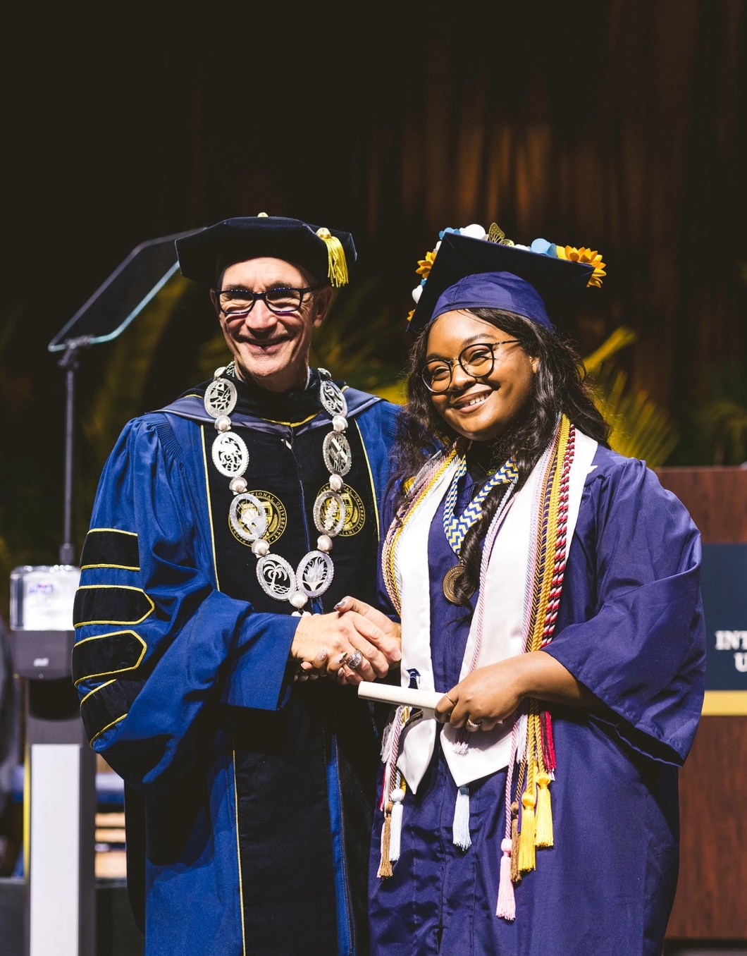 FIU President Kenneth Jessell shaking hands with graduate on stage