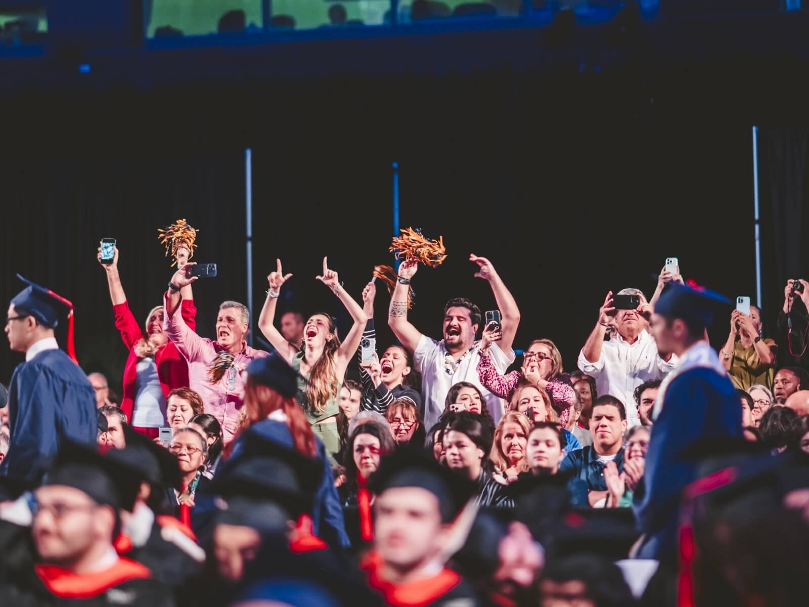 Audience members cheering and waving pom poms