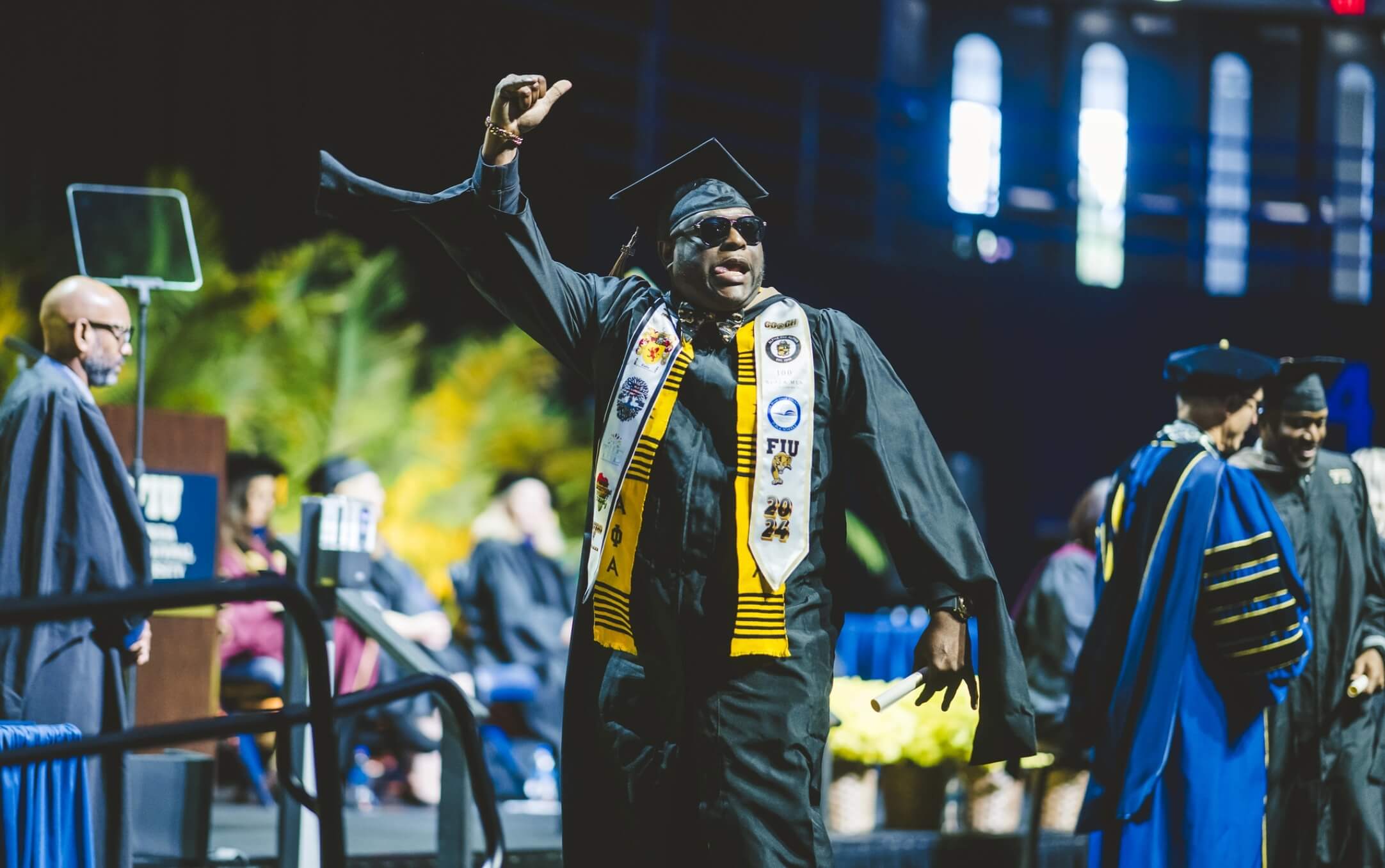 Graduate giving thumbs-up on stage