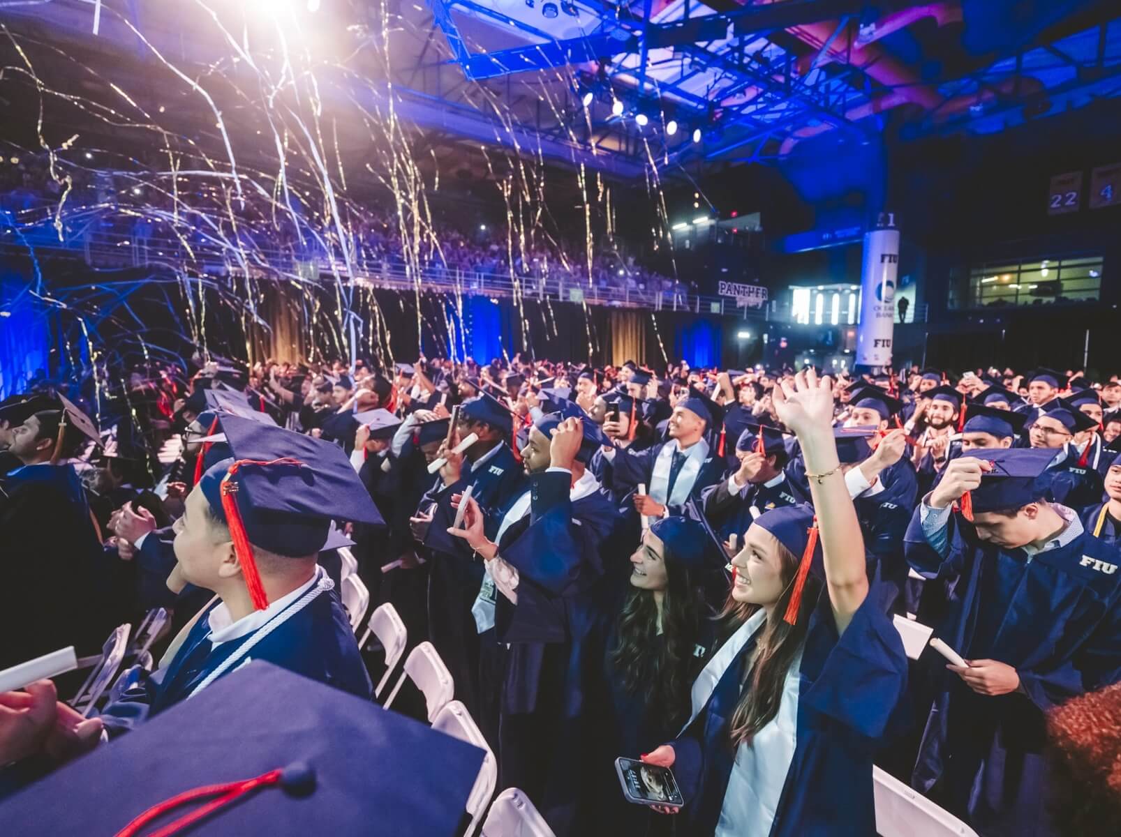 Crowd of graduates cheering as confetti drops