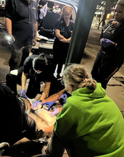  Medical students treat a wound during a street run with Dr. Chandra Jennings (far right) of Camillus Health Concern, and Rose Anderson (green sweater), a veteran street medicine ARNP who also assists students during outreach.