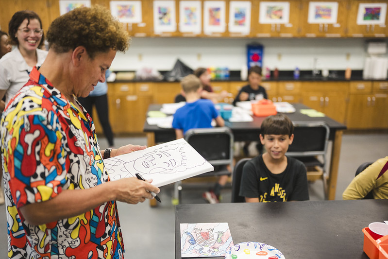 Romero Britto drawing a portrait of a camper.