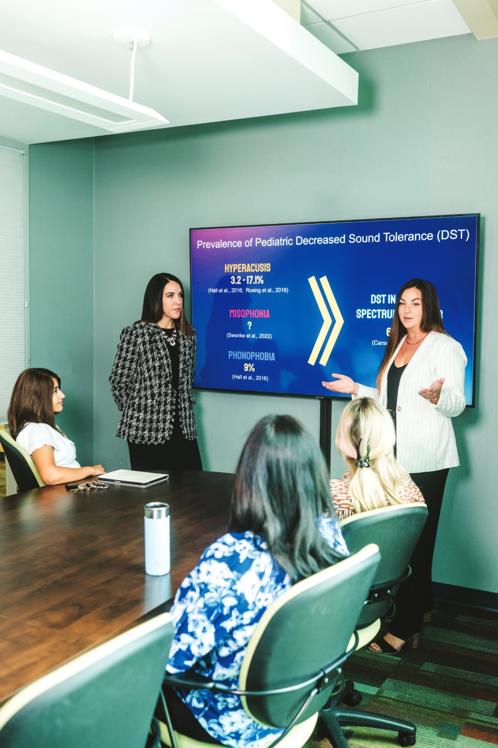 Two women presenting to a small group in a conference room. 